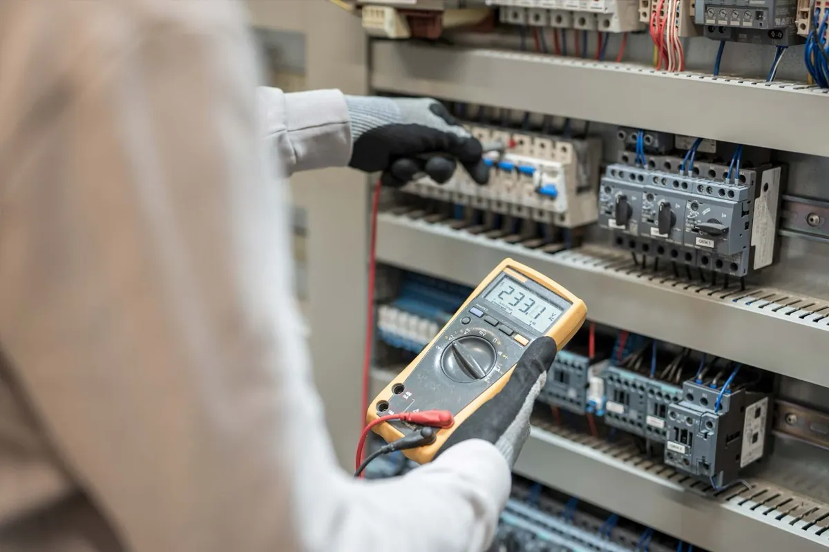 Elektriker misst an einem Schaltschrank