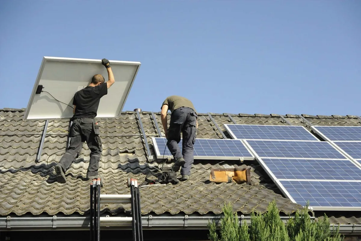 Zwei Monteure montieren Solarmodule auf einem Dach